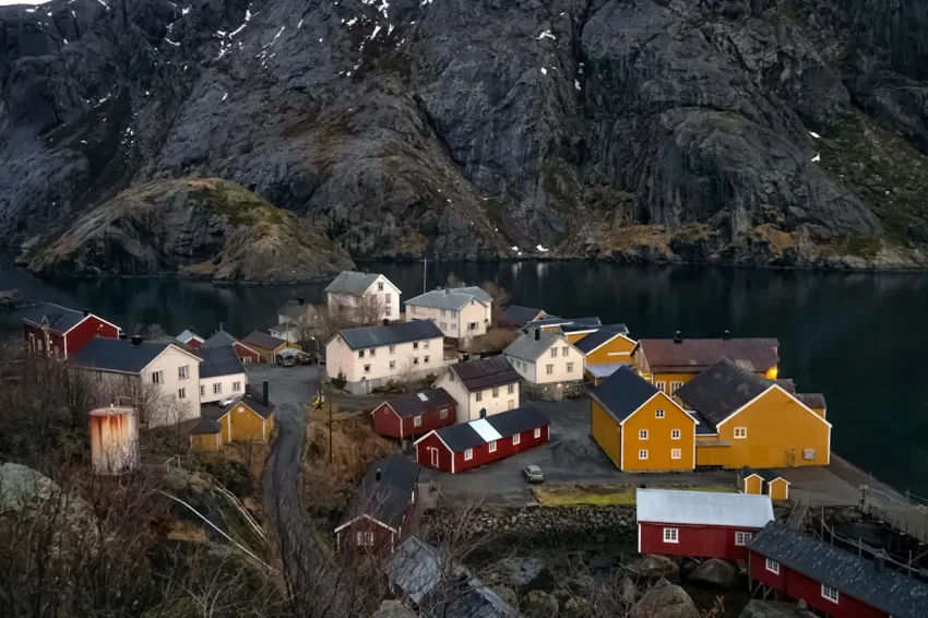 Nusfjord i Nordland med färgglada hus vid fjorden och branta berg i bakgrunden som illustrerar glesbygd och regionala förutsättningar som påverkar dieselpris och bränslekostnader i Norge.