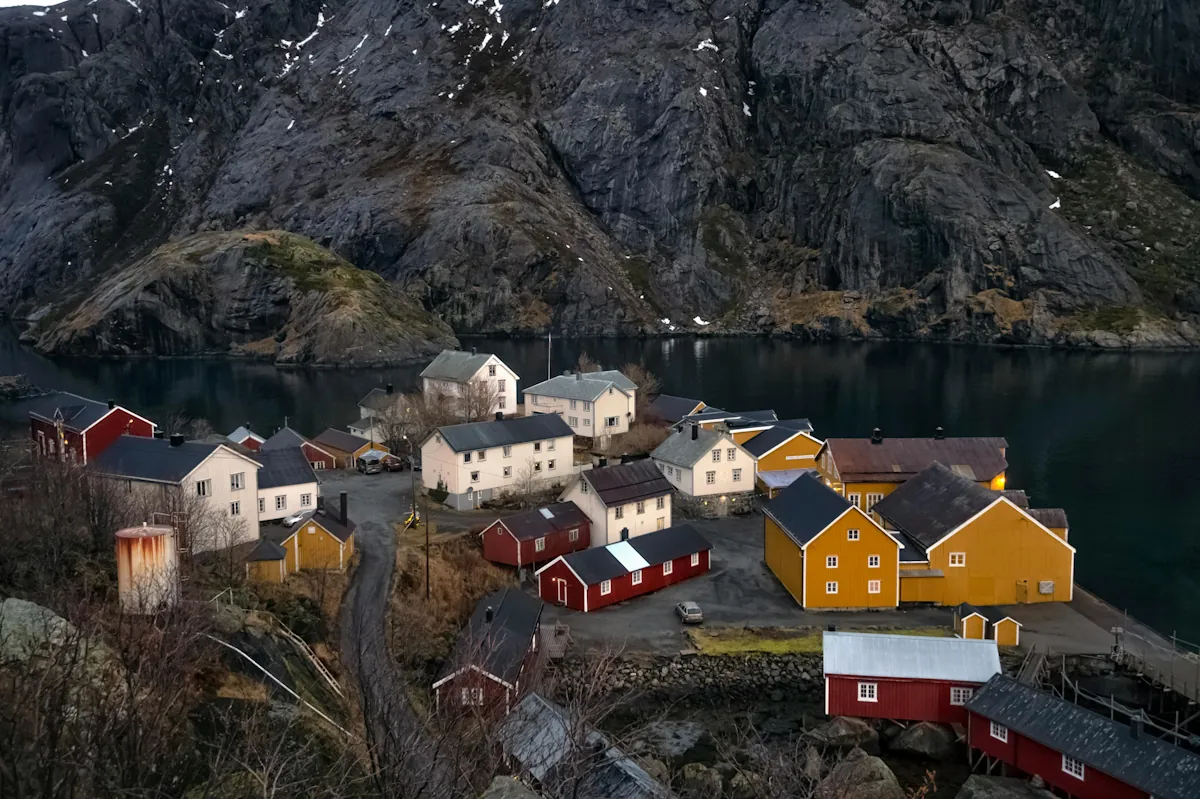 Nusfjord i Nordland med färgglada hus vid fjorden och branta berg i bakgrunden som illustrerar glesbygd och regionala förutsättningar som påverkar dieselpris och bränslekostnader i Norge.