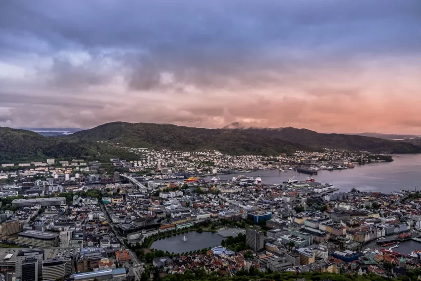 Panoramavy över Bergen med stadskärnan, hamnen och de omgivande bergen i mjukt kvällsljus